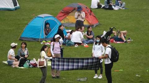 Woman wearing a face mask to help curb the spread of Covid-19 as her friends prepare to set up a picnic cloth on a scenic mountain in Yanqing, outskirt of Beijing, China