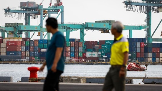 People walk past shipping containers at the port of Kaohsiung City, Taiwan