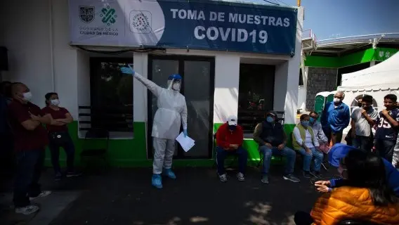 Health worker instructs the people waiting outside the medical center on how to get tested for COVID-9, at the Central de Abasto market of Mexico City
