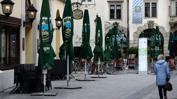 Woman passes stacked chairs and tables at the famous restaurant 'Hofbraeuhaus' downtown in Munich, as a month long partial lockdown becomes effective in Germany