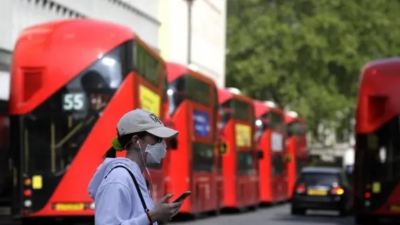 Woman passes parked buses near Oxford Street in London