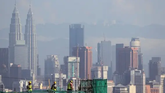 Workers labour on scaffolding at a construction site in Kuala Lumpur