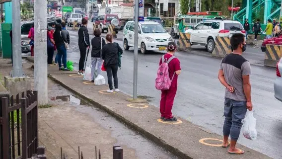People observe social distancing as they stand on circle shaped yellow markers while waiting for public transport to arrive, Philippines