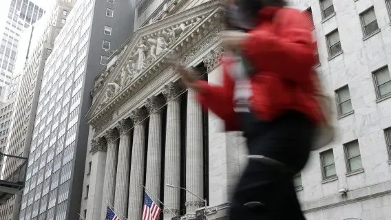 Pedestrians walk by the New York Stock Exchange after the opening bell at the NYSE on Wall Street in New York City