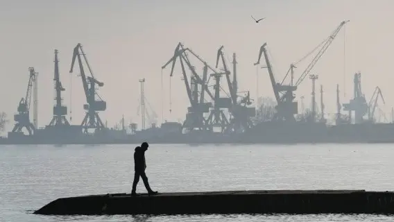 Man walks with harbour cranes in the background, at the trade port in Mariupol, Ukraine.