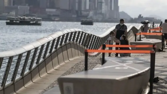 A lady help a child to put on face mask as a precautionary measure against the COVID-19 coronavirus, along Tsim Sha Tsui Promenade