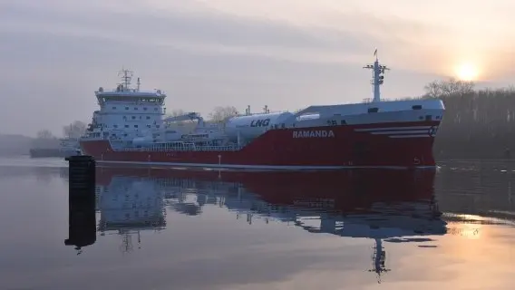 An LNG tanker travels through the Kiel Canal in Germany at sunrise
