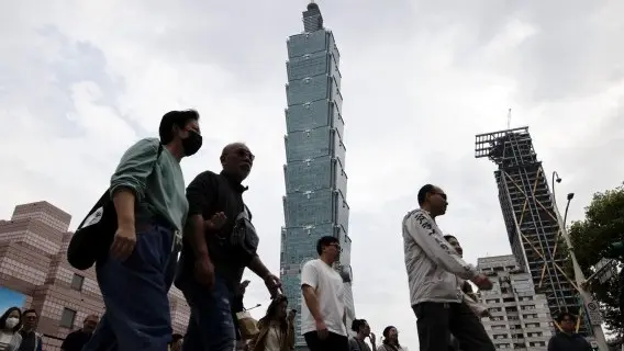 People walk past the Taipei 101 skyscraper in Taiwan,