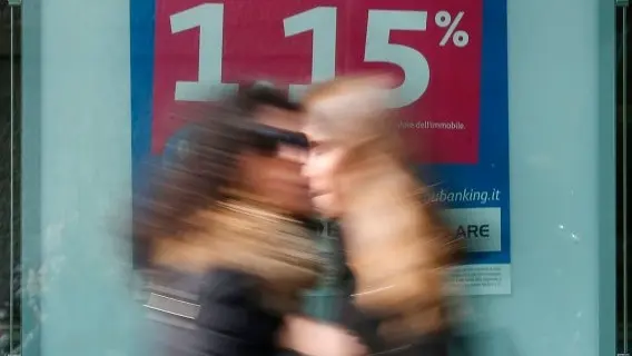 People walk past an poster advertising mortgages at a bank in Milan, Italy